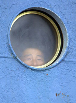 “바깥이 궁금합네다”남측이 제공하는 비료를 싣고 가기 위해 북한 화물선 백두산호가 22일 오후 울산항에 입항했다. 한 선원이 뱃전의 창문을 통해 울산항을 바라보고 있다. 울산=원대연 기자