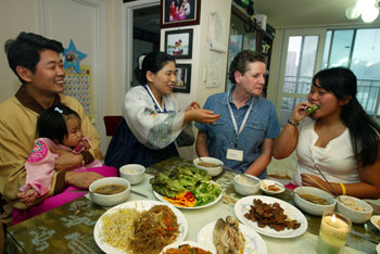 권호을 씨 부부(왼쪽)가 3일 루스 허스트 씨(오른쪽에서 두 번째)와 딸 김소희 양을 집으로 초대해 한국 음식 먹는 법을 설명해 주고 있다. 김동주 기자