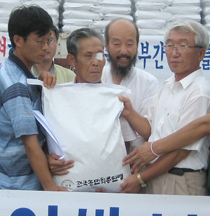 경기 평택농민회 회원들이 8일 홍한표 씨(오른쪽에서 세 번째)가 북한에 전달할 80kg들이 쌀 1000가마를 트럭에 옮겨 싣고 있다. 평택=연합