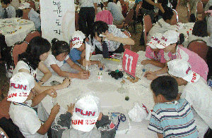 한국복지재단이 주최한 여름캠프에서 행사에 참여한 소년소녀가장들이 23일 SK 임직원들과 함께 마술 원리를 배우며 즐거운 한때를 보내고 있다. 사진 제공 한국복지재단