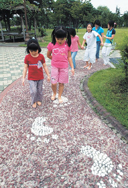 ‘놀이도 하고, 건강도 쌓고.’ 서울 영등포구 여의도동 여의도공원을 찾은 가족들이 26일 자갈과 맥반석 등이 깔린 산책로를 맨발로 걷고 있다. 박영대 기자