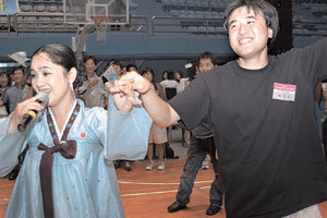 4일 인천대 실내체육관에서 열린 ‘남북 대학생 어울림 마당’에 참가한 북한 예술단원(왼쪽)이 고운 한복을 차려입고 노래를 부르자 남한 학생이 무대로 달려 나가 흥을 돋우고 있다. 사진 제공 인천대