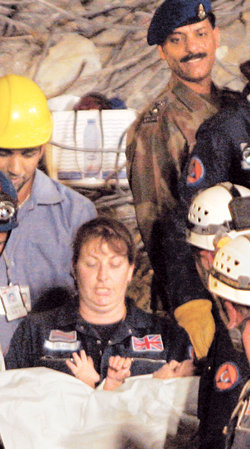 “살아있었구나”지진이 강타한 파키스탄 이슬라마바드의 붕괴된 건물 잔해 더미 밑에 갇혀 있던 두 살배기 여자아이(점선)가 참사 이틀 만인 10일 구조돼 한 여성 구조대원의 품에 안겨 있다. 이슬라마바드=AP 연합뉴스