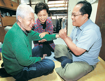 불의의 사고로 하반신이 마비된 김윤규 목사(오른쪽)가 24일 자원봉사자와 함께 전북 전주시의 한 독거노인을 찾아 물리치료를 해 주고 있다. 전주=연합뉴스