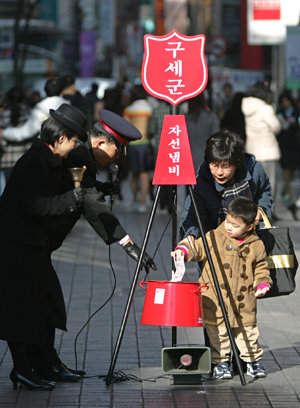 2005 구세군 자선냄비가 2일 각 거리마다 등장한 가운데 명동거리에서 한 어린이가 어머니와 함께 자선냄비에 성금을 넣고 있다. 연합