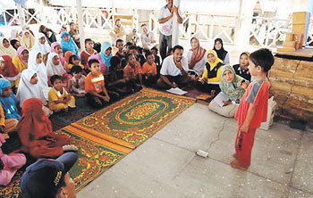 인도네시아 반다아체의 지진해일 이재민 캠프에서 집과 부모, 형제를 잃은 어린이들을 위한 작은 노래자랑 및 시낭송 대회가 열렸다. 관중이 한 소년 참가자의 목소리에 귀를 기울이고 있다. 사진 제공 크리스천 사이언스 모니터