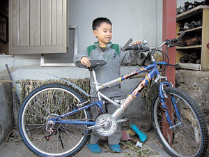 필리핀인 어머니가 가출해 큰집에서 살고 있는 박재선 군이 16일 어린이 보호단체 ‘세이브 더 칠드런’에서 선물로 받은 자전거를 보고 기뻐하고 있다. 사진 제공 세이브 더 칠드런