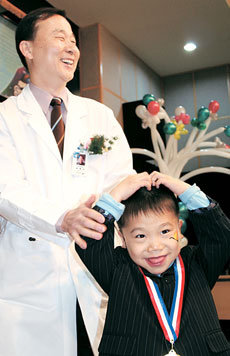 17일 경기 고양시 국립암센터 강당에서 치료종결 축하행사에 참석해 완치 기념 메달을 받은 한 어린이가 의료진을 향해 “사랑한다”며 하트 모양을 그리면서 환하게 웃고 있다. 고양=이동영 기자