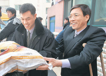 25일 서울 송파구 거여2동 임마누엘재활원 김경식 목사(오른쪽)가 ‘사랑의 쌀 나눔잔치’를 열고 지역 장애인들에게 쌀 20kg을 건네고 있다. 강병기  기자