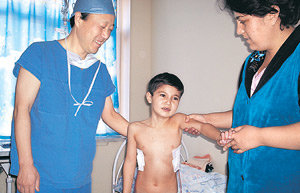 분당서울대병원 성숙환 교수(왼쪽)가 첫 수술 환자인 우크타모브 사르도르 군(가운데)을 수술 하루 만인 12일 병실에서 일으켜 세워 상태를 살피고 있다. 사르도르 군을 부축하고 있는 사람은 어머니 훌카르 밀리에바 씨. 타슈켄트=하준우 기자