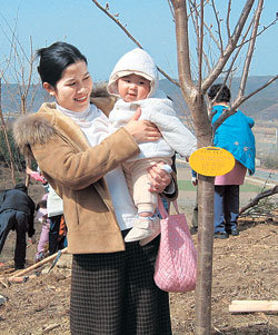 베트남 호찌민 출신 주부 응우옌티홍랑 씨가 나무를 심은 뒤 아들 김한남 군을 안고 기쁜 표정을 짓고 있다. 사진 제공 의성군
