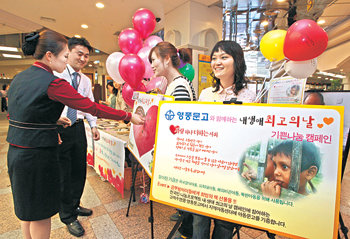 21일 서울 영풍문고 종로점에서 진행된 ‘내 생애 최고의 날’ 전 국민 나눔 프로젝트 행사에 참여한 한 여성이 보드판에 동전을 붙이고 있다. 김동주 기자