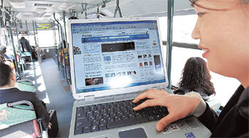“신기해요”한 대학생이 서울 연세대 앞을 달리는 버스 안에서 휴대인터넷(와이브로)에 접속해 동영상을 내려받고 있다. KT는 5월 말까지 3000명의 고객을 대상으로 시범 서비스를 한 뒤 6월부터 상용 서비스를 할 계획이다. 사진 제공 KT