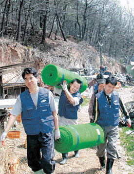 충남 천안 삼성SDI 플라스마 디스플레이 패널(PDP) 사업장의 어깨동무 봉사팀원들이 인근 농촌 지역에서 토끼장 깔판으로 쓰일 천을 들어 옮기고 있다.