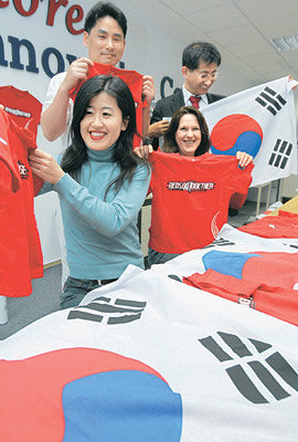 토고와의 월드컵 첫 경기를 하루 앞둔 12일 독일 프랑크푸르트 외곽 오버우르젤의 재독한인총연합회 월드컵 응원 본부에서 한국 교민과 독일 팬들이 응원에 사용할 태극기와 붉은색 티셔츠를 들어 보이고 있다. 프랑크푸르트=연합뉴스