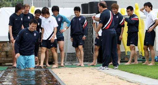 고생한 ‘발’ 달래기 태극전사들이 21일 독일 레버쿠젠의 바이아레나 보조구장에서 훈련을 마친 뒤 딕 아드보카트 감독(가운데 등 보이고 서 있는 사람)의 지시로 족욕탕에 차례로 발을 담그고 있다. 물밑에는 자갈이 있어 지압효과가 있다고. 레버쿠젠=연합뉴스