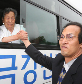 30일 금강산호텔에서 열린 남북이산가족 작별행사를 마친 뒤 28년 만에 북측의 아들 김영남 씨(오른쪽)를 상봉한 어머니 최계월 씨가 남측으로 돌아가는 버스에 탄 뒤 차창 밖으로 김 씨의 손을 꼭 잡은 채 울음을 참고 있다. 이훈구 기자