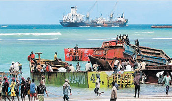 3일자 미국 뉴욕타임스에 실린 소말리아 최대 항구 엘마안의 풍경. 해변에 정박한 여러 척의 선박과 그 주변을 분주히 오가는 현지인들이 언제 해적선과 해적으로 돌변할지는 아무도 모른다. 멀리 이곳에 끌려와 억류 중인 상선이 보인다. 사진 출처 뉴욕타임스