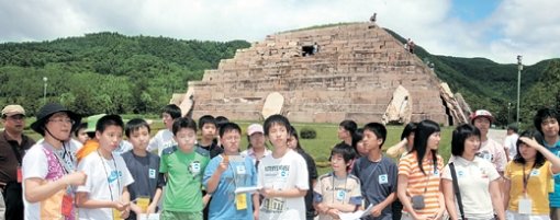 23일 중국 옛 고구려 수도 지안 유적지를 찾은 역사탐방단 학생들이 유적지 안내 설명을 듣고 있다. 뒤에 보이는 ‘피라미드’ 모양의 돌더미가 장군총. 지안=이훈구  기자