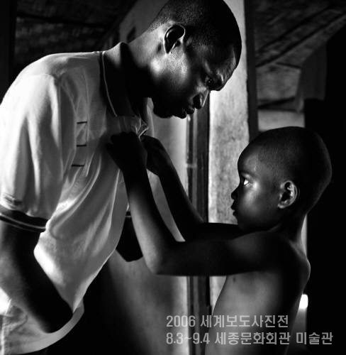 아프리카 내전의 상흔. 아이가 손목이 잘린 아버지의 옷 단추를 끼우고 있다.