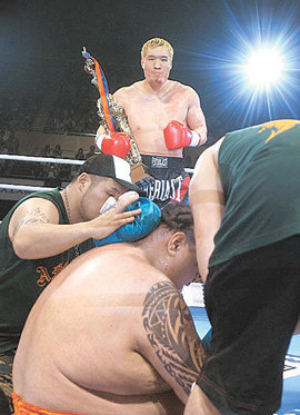 최홍만(뒤)이 아케보노(앞 가운데)를 2회 57초 만에 KO시킨 뒤 트로피를 들고 캔버스에서 일어나지 못하고 뒤통수에 얼음찜질을 하고 있는 아케보노를 지켜보고 있다. 연합뉴스