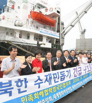 北으로 가는 구호품민족화해협력범국민협의회 회원들이 16일 인천항에서 북한 수해지역에 보낼 밀가루 40t과 의류 등 3억2000만 원 상당의 구호물품을 실은 화물선 앞에서 선적식을 하고 있다. 이 배는 이날 북한 평남 남포항으로 출발했다. 인천=연합뉴스
