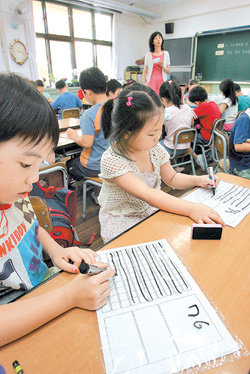 서울 영도초등학교 1학년 7반의 수학 시간. 클리어 파일 속지와 하드보드지를 활용한 숫자 쓰기 판은 담임교사의 아이디어와 학부모 도우미의 합작품이다. 어린이들이 고사리손으로 숫자만큼 빈칸을 채우고 있다. 신원건 기자