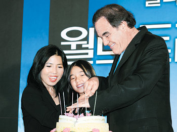 영화 ‘월드트레이드센터’의 개봉을 앞두고 방한한 올리버 스톤 감독(오른쪽)이 15일 60회 생일을 맞아 한국인 아내 정선정 씨, 딸 타라 양과 함께 떡 케이크를 자르고 있다. 사진 제공 영화사 숲