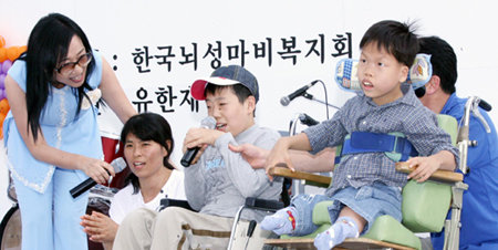 한국뇌성마비복지회는 21일 서울 여의도 한강시민공원 수변마당에서 전국의 뇌성마비 장애인과 가족이 참가한 가운데 24회 ‘오뚝이 축제’를 열었다. 이번 행사에 찬조 출연한 가수 신형원 씨(왼쪽)가 노래를 부르자 행사 참가자들이 즐거워하며 따라 부르고 있다. 사진 제공 한국뇌성마비복지회