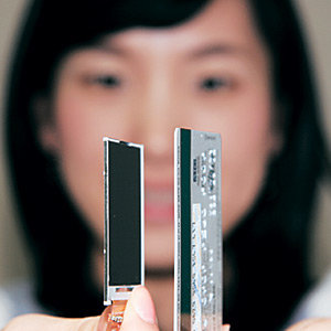 한 여성이 LG필립스LCD가 개발한 휴대전화용 초박막트랜지스터 액정표시장치(TFT-LCD·왼쪽)를 비슷한 두께의 신용카드와 함께 들고 있다. 사진 제공 LG필립스LCD