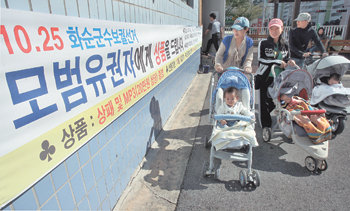 “투표도 하고 선물도 받고” 25일 인천 남동을과 전남 해남-진도 국회의원 보궐선거를 비롯해 전국 9곳에서 재·보궐선거가 치러졌다. 이날 전남 화순군수 보궐선거가 치러진 화순 제10투표소 앞에 ‘3대 이상 가족이 투표에 참가하는 가정에 MP3플레이어를 선물로 제공한다’는 내용의 현수막이 걸려 있다. 각 지역 선거관리위원회는 다양한 인센티브 방안을 내놨다. 화순=박영철  기자