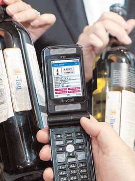 휴대전화를 이용한 무선인식(RFID) 시범 서비스가 시작됐다. 휴대전화기가 와인 병의 RFID 칩을 인식해 와인의 종류와 생산지 등 기본 정보를 알려주는 모습. 사진 제공 KTF