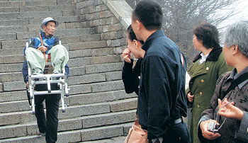 ‘지게 효자’ 이군익 씨가 아버지 이선주 씨를 지게에 태워 중국 타이산을 오르는 광경을 중국인들이 유심히 바라보고 있다. 연합뉴스