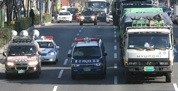 4일 울산 남구 옥동 울주군청 앞 편도 4차로 도로에서 경찰 차량(가운데)이 “운송 거부에 동참하라”고 종용하는 화물연대 울산지부 소속 선전차량을 4차로로 몰아붙이면서 화물을 실어 나르는 트럭(오른쪽)을 호위하고 있다. 울산=연합뉴스