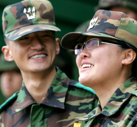 8일 오후 육군 제8사단 신병교육대에서 열린 중대장 이·취임식에서 전임 중대장인 서지영 대위(오른쪽)가 남편인 이정규 대위에게 지휘권을 넘겨주며 함께 웃고 있다. 연합뉴스