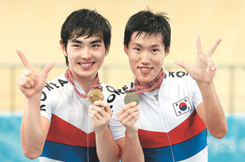 사이클 단짝 “나 금 2개” “난 3개”장선재(오른쪽)와 박성백이 14일 남자 사이클 트랙 매디슨(50km)에서 금메달을 획득한 뒤 나란히 손가락으로 자신의 이번 대회 금메달 획득 수를 표시하고 있다. 장선재는 4km 개인추발, 단체추발 우승에 이어 3관왕, 박성백은 단체추발에 이어 2관왕에 올랐다. 도하=강병기 기자