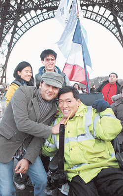 전동 휠체어를 입으로 조종해 유럽을 종단 중인 중증 장애인 최창현 씨. 2일 프랑스 파리의 에펠탑 광장에 도착해 격려해 주는 한 외국인과 기념 사진을 찍었다. 파리=금동근 특파원