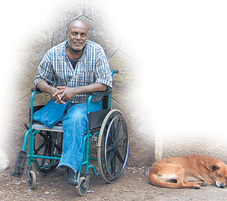 다리 한쪽을 잃고 휠체어에 의지하고 있는 에티오피아의 한 장애인. 옆에는 개 한마리가 축 늘어진 채 잠을 자고 있다.