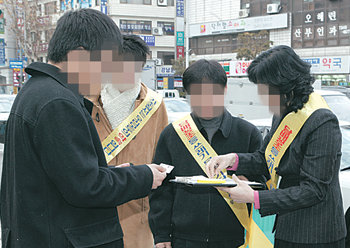 강남구 단속반원이 담배꽁초를 길가에 버린 20대 남자(왼쪽)에게 5만 원의 과태료 고지서를 발부하고 있다. 사진 제공 강남구청