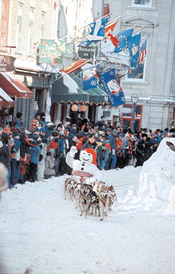 퀘벡시티의 겨울축제인 ‘카나발 드 퀘벡’의 마스코트인 보놈(좋은 사람이라는 뜻)이 개썰매를 타고 가며 관광객을 향해 인사를 건네고 있다. 북미의 유일한 성곽도시인 올드퀘벡의 생루이 거리.