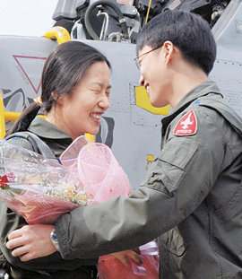 국내 최초로 여성 전투기 편대장이 된 공군 제8전투비행단 소속 박지연 대위가 22일 최종 평가 관문을 통과한 뒤 남편 정준영 대위에게서 축하 꽃다발을 받고 있다. 원주=연합뉴스