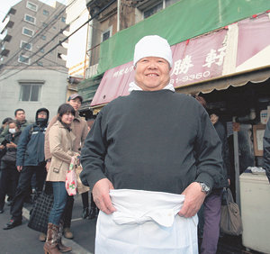 일본 라면의 일종인 ‘쓰케멘’의 원조 야마기시 가즈오 씨가 자신의 가게 ‘다이쇼켄’ 앞에서 보도진을 향해 미소 짓고 있다. 도쿄=천광암  특파원