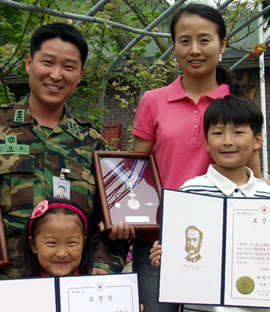 조정남 대위와 부인 김정금 씨가 대한적십자사로부터 받은 헌혈 유공포장 금장과 은장을 자녀들과 함께 들어 보이고 있다. 연합뉴스