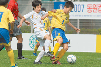 구룡초등학교의 김창준(가운데)과 신용산초등학교의 김반석(오른쪽)이 공을 다투고 있다. 두 팀의 경기에서는 치열한 공방 속에 8골이 터졌다. 신원건  기자