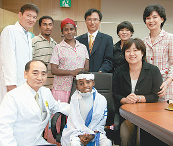 20일 서울 영동세브란스병원에서 아비 아사미뉴 군이 박희완 병원장(앞줄 왼쪽) 등 의료진과 후원자들의 축하를 받고 있다. 사진 제공 굿네이버스