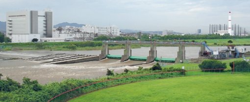 일본의 수도권에 있는 가나가와 현 사무카와 하천 정수장의 잔디 야구장(오른쪽) 맞은편에는 대기업인 캐논과 중소기업의 공장들이 하천을 따라 자리 잡고 있다. 기둥이 높게 솟은 이 지역 쓰레기 소각장도 정수장 상류에서 문제 없이 가동되고 있다. 가나가와=이동영 기자