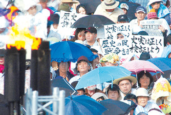 지난달 29일 일본 오키나와 현 기노완 시 가이힌 공원에서 열린 ‘역사왜곡 규탄 현민 궐기대회’에 참석한 주민들이 ‘역사적 사실은 정확히 검증하자’ 는 구호 등이 적힌 피켓을 들고 심각한 표정으로 앉아 있다. 기노완=AP 연합뉴스