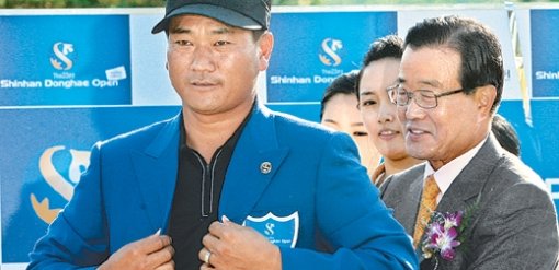 제23회 신한동해오픈에서 특유의 뒷심으로 정상에 오른 ‘탱크’ 최경주(왼쪽)가 우승자에게 주는 파란색 재킷을 라응찬 신한금융지주 회장에게서 건네받아 입고 있다. 용인=연합뉴스