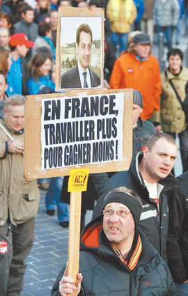 국영철도 근로자 시위 프랑스 전역에서 대중교통 파업이 시작된 14일 북부 릴의 프랑스국영철도(SNCF) 소속 근로자가 니콜라 사르코지 대통령의 사진 아래 ‘프랑스에선 더 적게 벌기 위해 더 많이 일한다’고 쓴 피켓을 들고 시위를 벌이고 있다. 릴=로이터 연합뉴스