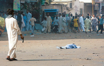 경찰-시위대 충돌로 희생된 어린이베나지르 부토 전 총리의 가택 연금에 반대하는 시위가 벌어진 15일 파키스탄 카라치에서 누군가가 쏜 총에 맞아 사망한 한 어린이를 총을 든 한 남자와 시위대가 바라보고 있다. 카라치=로이터 연합뉴스